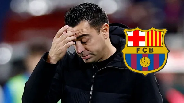 Xavi se lamenta y mira hacia abajo, a su derecha el escudo del FC Barcelona