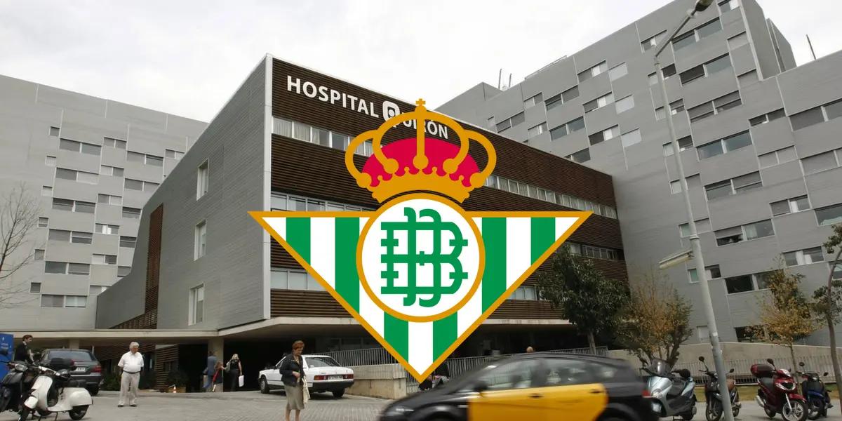El escudo del Real Betis con un hospital de España de fondo.