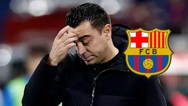 Xavi se lamenta y mira hacia abajo, a su derecha el escudo del FC Barcelona
